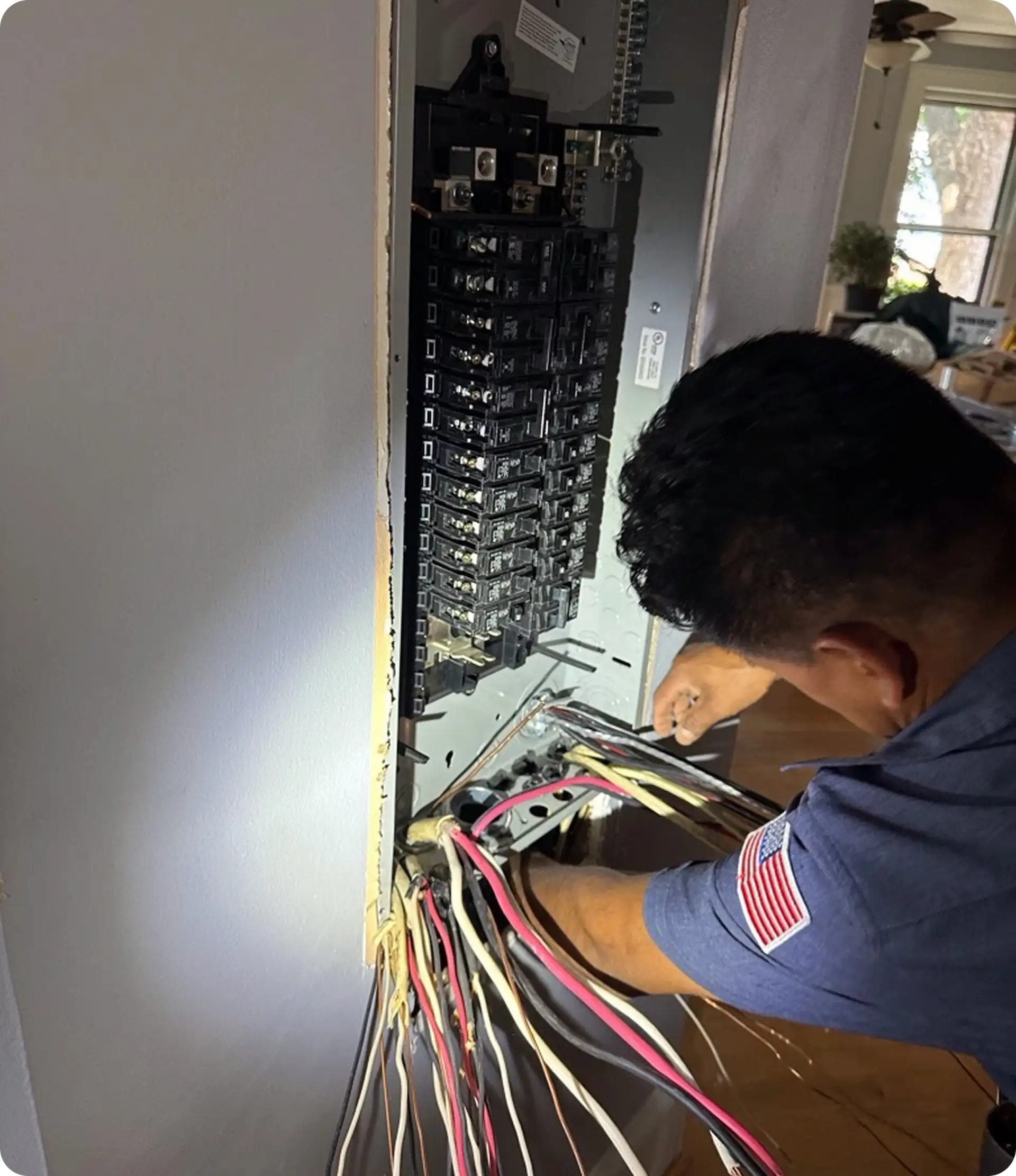 Electrician working on residential electrical panel wiring and circuit breaker installation