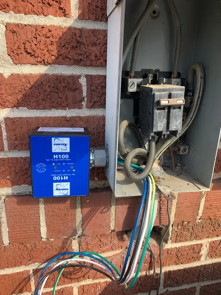 Residential electrical panel with surge protector installation on exterior brick wall